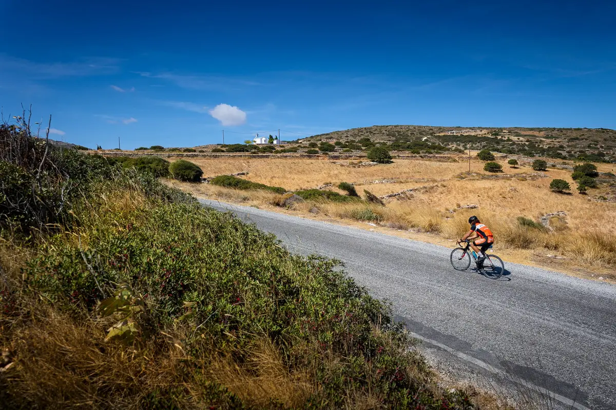 A cyclist on a quiet road through dry fields under a deep blue sky